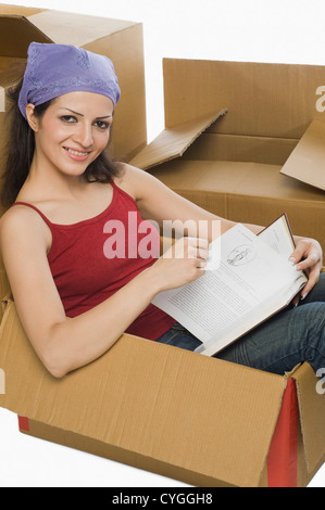 Ritratto di una donna in possesso di un libro in una scatola di cartone Foto Stock