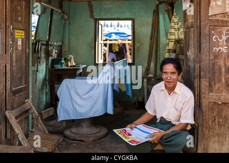 Myanmar, un barbiere in Hleku street market, lungo la strada che da Yangon a Bago. Foto Stock