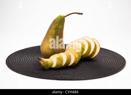Una pera intera e una pera affettata sul posto nero mat Foto Stock