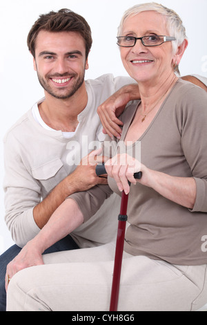 Giovane uomo accovacciato da donna anziana Foto Stock