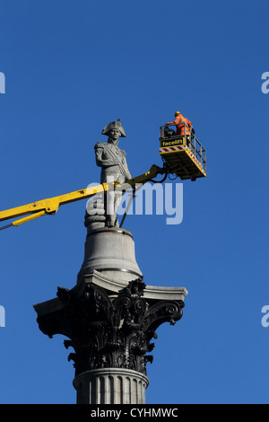 Un builder raffigurato su una gru guardando Nelison la colonna a Londra in Trafalgar Square. Foto Stock