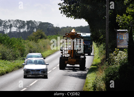 Vetture il sorpasso di un veicolo agricolo nonostante il passaggio di un pub ingresso su una strada nel GLOUCESTERSHIRE REGNO UNITO Foto Stock