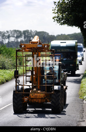 Vetture bloccato dietro un veicolo agricolo su una strada nel GLOUCESTERSHIRE REGNO UNITO Foto Stock