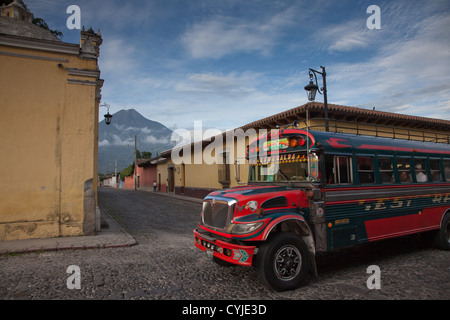 Coloratissimo pollo contrasto autobus la splendida architettura antica e le strade lastricate di Antigua, Guatemala. Foto Stock