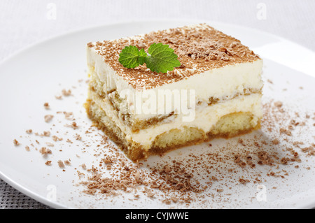 Il tiramisù - Classico dolce con il caffè sulla piastra bianca. Guarnite con foglie di menta. Foto Stock