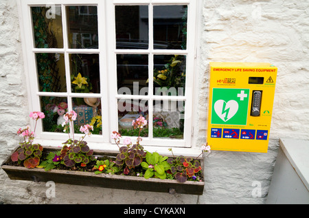 Un cuore cardiaco defibrillatore disponibile al pubblico sulla parete in villaggio Clun nello Shropshire, Regno Unito Foto Stock