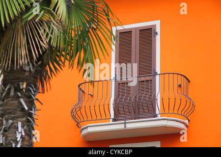 Il balcone di una casa con una facciata di colore arancione a Sirmione sul Lago di Garda, Regione di Brescia, Lombardia, Italia Foto Stock