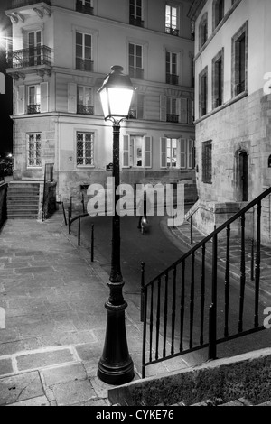 Donna Bicicletta Equitazione lungo il lato illuminato strada di Parigi e dell' Ile-de-France, Francia Foto Stock