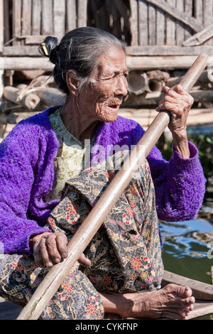 Myanmar Birmania. Vecchia donna Intha Paddling la sua barca, Lago Inle, Stato di Shan. Foto Stock