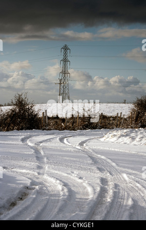 Un paesaggi innevati con un pilone accanto a una coperta di neve road, con le vie utilizzate come linee di leader Foto Stock