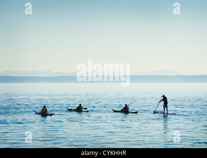 Kayakers e un paddleboarder convergono off Port Townsend, Washington per celebrare la barca di legno Festival su una calma, giorno chiaro. Foto Stock