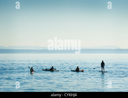 Kayakers e un paddleboarder convergono off Port Townsend, Washington per celebrare la barca di legno Festival su una calma, giorno chiaro. Foto Stock