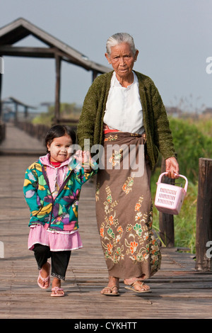 Myanmar Birmania. Nonna e nipote Camminare vicino a 'ponte galleggiante', Lago Inle, Stato di Shan. Foto Stock