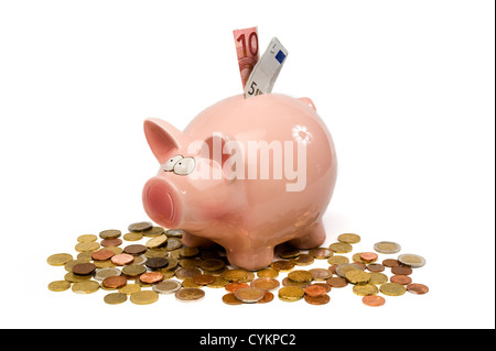 Salvataggio di un maiale è in piedi tra un sacco di monete metalliche in euro Foto Stock