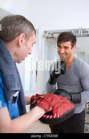 Boxer a fare pratica con il trainer in palestra Foto Stock