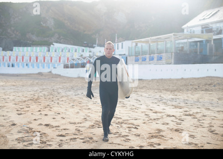 Surfer scheda portante sulla spiaggia Foto Stock