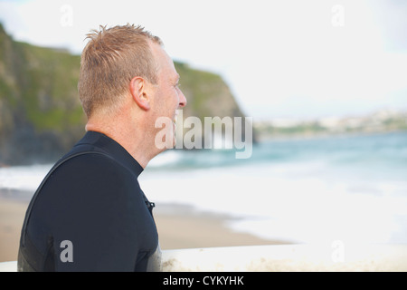 Surfer indossando muta sulla spiaggia Foto Stock