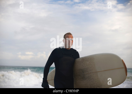 Surfer scheda portante sulla spiaggia Foto Stock