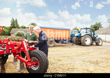 Gli agricoltori la regolazione delle macchine in campo Foto Stock