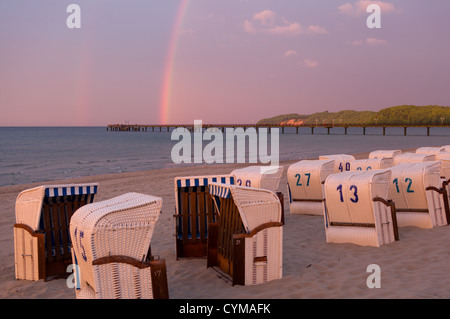 Beach lounge chair in il tramonto con un arcobaleno presso la spiaggia della località balneare di Binz sull'isola di Rügen Mar Baltico Foto Stock