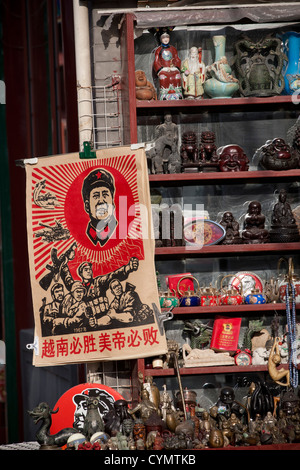 Un poster del Presidente Mao in vendita in un negozio a fianco di figure religiose e le icone in strada Liulichang, Pechino, Cina. Foto Stock
