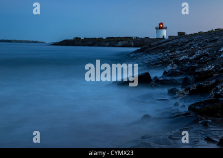 Burry Port faro prese al tramonto con il mare sfocata a causa di una lunga esposizione Foto Stock