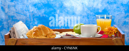 La deliziosa prima colazione sul vassoio costituito da caffè, succo di arancia, succo di mela, croissant, marmellata e burro Foto Stock