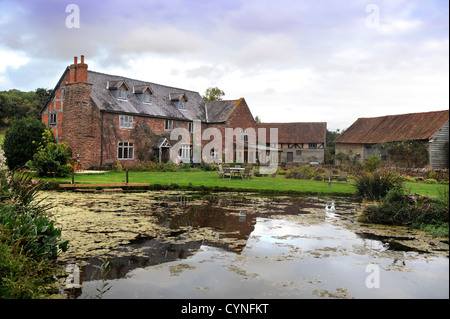 Una casa colonica con un laghetto in giardino in Herefordshire UK Foto Stock