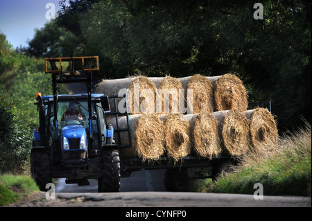 Un trattore il traino di un rimorchio di balle di fieno nel GLOUCESTERSHIRE REGNO UNITO Foto Stock