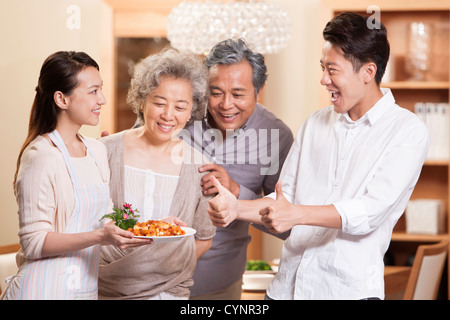 La famiglia felice apprezzando giovane donna la cottura Foto Stock