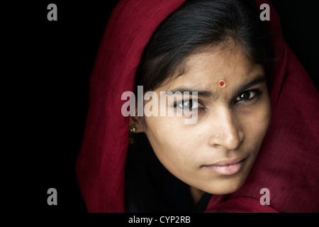 Ragazza indiana indossando un velo di colore rosso su sfondo nero. Andhra Pradesh, India Foto Stock