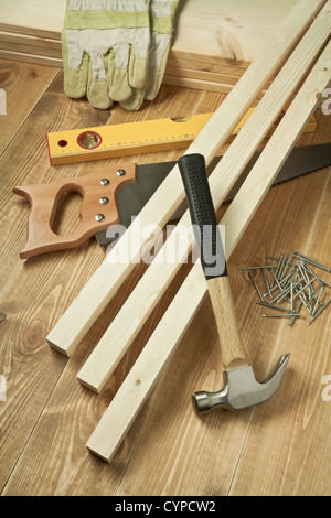 Martello, sega, livello, guanti, tavole e chiodi sul pavimento in legno Foto Stock