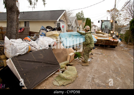 Un Seabee assegnato alla Naval Mobile Battaglione di costruzione 11, da Gulfport, Miss., carichi di un bulldozer piena di detriti che è stata causata dall'uragano Sandy durante per i soccorsi in Staten Island, N.Y., davanti a una previsione temporale. NMCB-11 è operante sotto Foto Stock