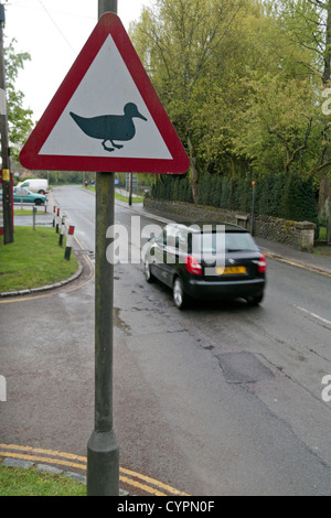 Auto passando un 'ducks crossing' triangolo di avvertimento su una strada di Bourton sull'acqua, Gloucestershire, UK. Foto Stock