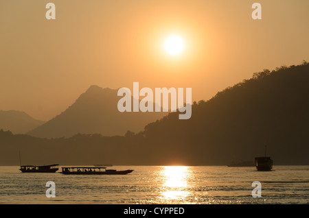 LUANG PRABANG, Laos - tramonto sul Mekong. Il fiume Mekong scorre vicino alla storica città di Luang Prabang nel Laos settentrionale. Il fiume, uno dei principali corsi d'acqua del sud-est asiatico, svolge un ruolo cruciale nell'ecologia, nell'economia e nella cultura della regione. Luang Prabang, patrimonio dell'umanità dell'UNESCO, si trova alla confluenza dei fiumi Mekong e Nam Khan. Foto Stock