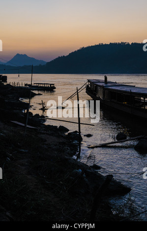 Fiume Mekong al tramonto Luang Prabang Laos // LUANG PRABANG, Laos - il fiume Mekong scorre vicino alla storica città di Luang Prabang nel Laos settentrionale al tramonto. Il Mekong, uno dei principali corsi d'acqua del sud-est asiatico, si estende per circa 4.350 chilometri dall'altopiano tibetano al Mar Cinese meridionale, sostenendo milioni di persone in sei paesi. Luang Prabang, patrimonio dell'umanità dell'UNESCO dal 1995, si trova alla confluenza dei fiumi Mekong e Nam Khan. L'antica capitale reale fu sede del regno di LAN Xang e rimane famosa per la sua ben conservata t buddista Foto Stock