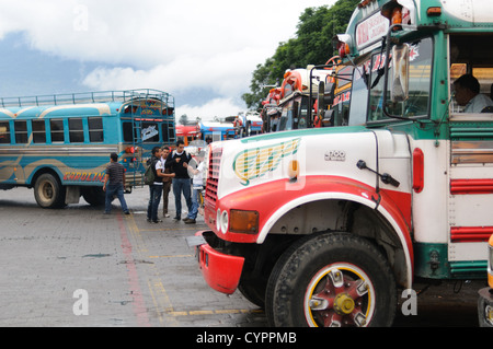 ANTIGUA GUATEMALA, Guatemala - autobus di pollo allineati dietro il Mercado Municipal (mercato cittadino) ad Antigua, Guatemala. Da questo ampio interscambio centrale di autobus, i percorsi si irradiano attraverso il Guatemala. Spesso verniciati con colori vivaci, gli autobus a base di pollo sono scuolabus americani adattati e forniscono un mezzo di trasporto economico in tutto il paese. Foto Stock