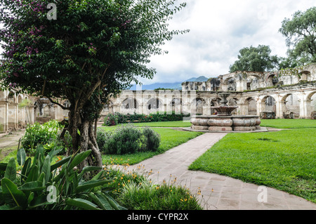Rovine del convento di Santa Clara cortile Fontana Antigua Guatemala // ANTIGUA, Guatemala - le rovine del monastero e della chiesa di Santa Clara sono un silenzioso testamento della storia coloniale. La facciata ornata e le pareti sbriciolate, adagiate su uno sfondo di vegetazione lussureggiante e vulcani lontani, esemplificano l'architettura barocca e le sfide sismiche che caratterizzano il paesaggio urbano di Antigua, Patrimonio dell'Umanità dell'UNESCO. Foto Stock