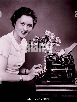 Donna sorridente digitando su una macchina da scrivere, circa 1930 Foto Stock