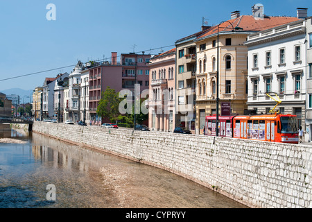 Edifici lungo Obala dei Kulina Bana strada sulla sponda nord del fiume Miljacka a Sarajevo, nella capitale della Bosnia ed Erzegovina. Foto Stock