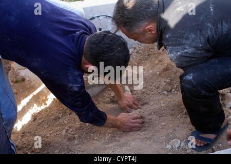 8 novembre 2012 - Aleppo, Siria: Uomini coprono una grave durante un servizio funebre per un uomo ucciso da un cecchino in Kadi Askar quartiere di Aleppo. Foto Stock