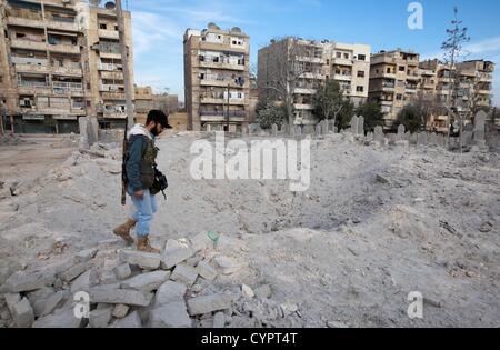 8 novembre 2012 - Aleppo, Siria: un libero esercito siriano fighter ispeziona un cratere da un MIG attentato in un cimitero di Kadi Askar quartiere di Aleppo. Nessuno è stato ferito in questo attacco notturno. Foto Stock