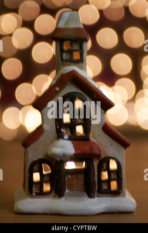 Una cena a lume di candela casa natale ornamento con luci scintillanti in background Foto Stock