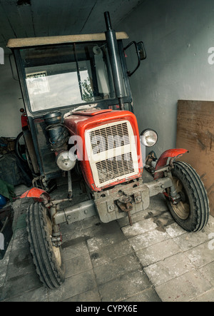 Il vecchio trattore arrugginito in un garage. Foto Stock