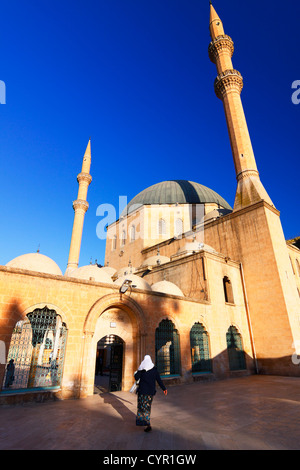 Donna con hejab immettendo il-Mevlid Halil ho Camii moschea dell'Degah complesso dalla Golbasi area di Sanliurfa, Turchia Foto Stock