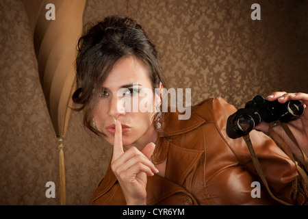 Bella Spy con un binocolo in Cappotto di pelle Foto Stock