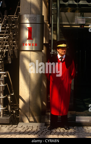 Un portiere nel tradizionale rosso lungo soprabito sorge al di fuori del Lloyds of London indirizzo nella City di Londra, Foto Stock