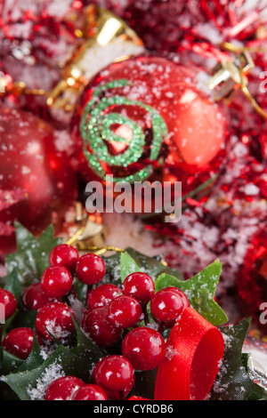 Bella disposizione di Natale con rosso e baubles Holly bacche coperte da neve. Foto Stock