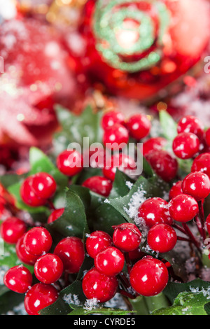 Disposizione di natale con red winterberries e baubles colorate coperte da neve. Foto Stock