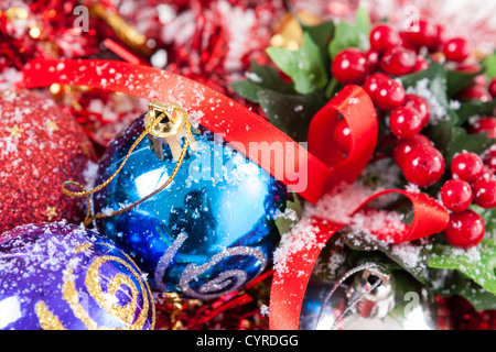 Bella disposizione di Natale con colorate e baubles Holly bacche coperte da neve. Foto Stock